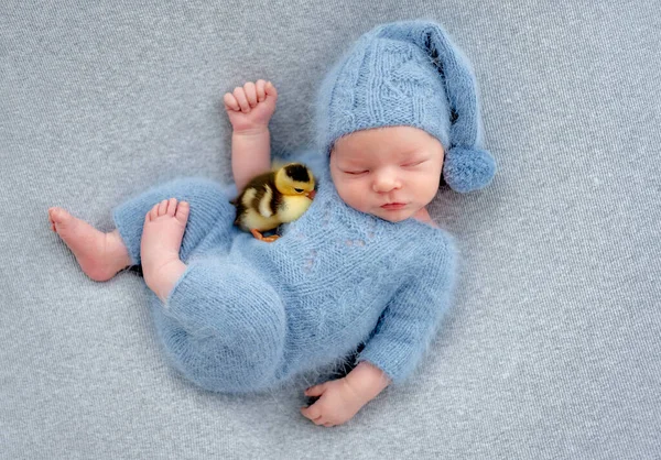 刚出生的男婴和小鸭睡在一起 穿着针织帽子和服装睡觉的可爱的幼儿 — 图库照片