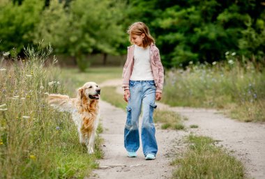 Golden Retriever köpeği olan genç bir kız doğada yürüyor. Saf evcil köpek labradoru şirin çocuk yazın parkta.