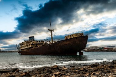 Kıyıya yüzen bir turistik, Lanzarote eski paslı endüstriyel İspanyol gemisi,