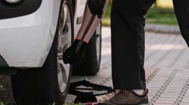 Tamirci, Wrench ile tekerlek cıvatasını sökmek için özenle çalışıyor.
