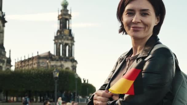Młoda Kobieta Uśmiecha Się Niemiecką Flagą Ręku Tle Rozmazanego Miasta — Wideo stockowe