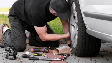 Sürücü, sokaktaki araçları kullanarak araba tamir ediyor.