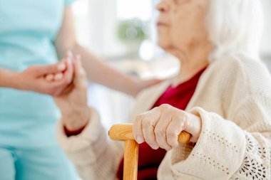 Hemşireler, yaşlı bir kadının kullandığı haplarla yaşlı kadınların elini tutarken yakın plan çekimde yakalanırlar.