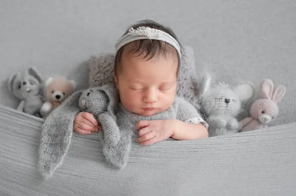 新生児の少女はスタジオで赤ちゃんの写真撮影中に玩具とブランケットの下で眠る — ストック写真