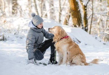 Genç kız ve altın av köpeği kış boyunca karla kaplı ormanda birlikte otururlar.