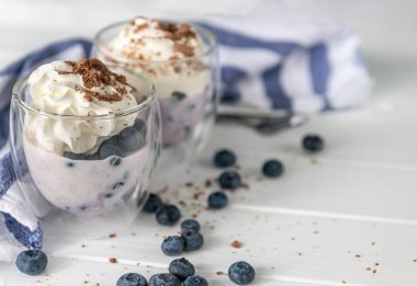 Yoğurt yaban mersini ve Beyaz ahşap zemin üzerinde çikolata ile gelen tatlı