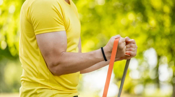 ManS Hands With Sports Bands Pump Biceps In Close-Up Outdoor Sports