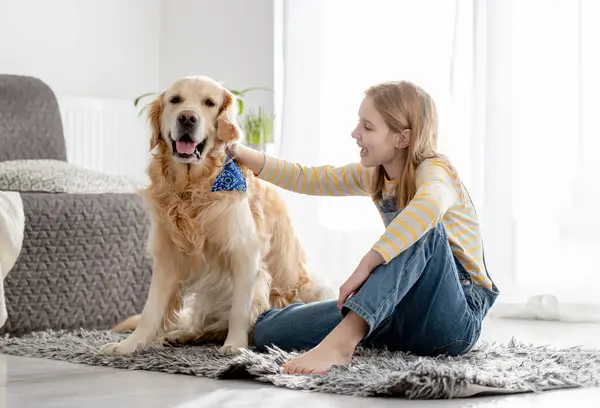 Girl With Golden Retriever Sits On Floor In Room Playing With Dog