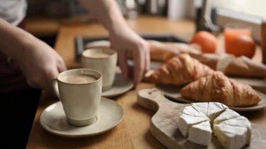 Kız kahvaltıda kahve kapuçino ve kruvasan alır. Mutfaktaki masada brie peyniri var. Kremalı espresso ve hamur işiyle nefis bir sabah yemeği.