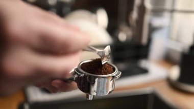 Girl hand holding portafilter with fresh coffee to make fresh aromatic cappuccino at home. Aroma espresso preparation process with professional latte maker machine