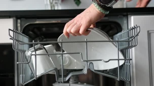 여자는 클로즈업 샷에서 세탁기에서 접시를 취한다 — 비디오