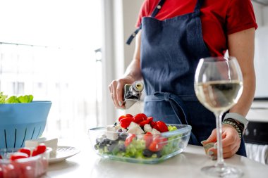 Yunan salatasına Çiselemeli Kadın Elleri Yağı. Lezzetli Vejetaryen Yemekleri