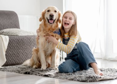 Golden Retriever Dog 'lu bir kız evde köpekle portre çektirmek için poz veriyor.