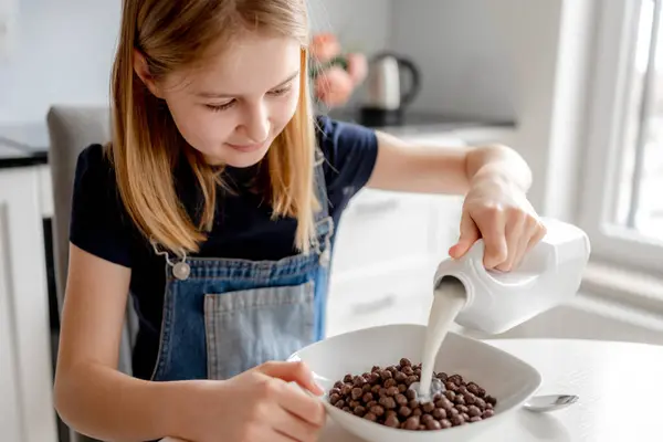 Sweet Girl Pours Milk Bowl Dry Breakfast Kitchen — Stock Photo, Image