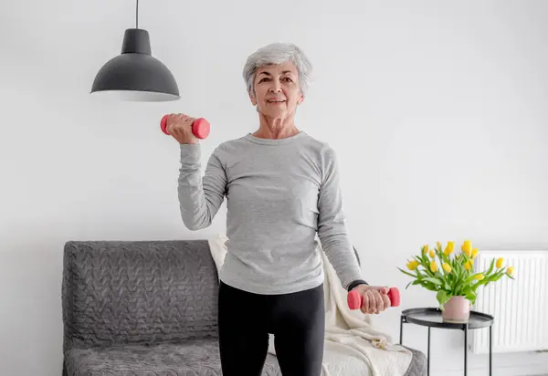 年长甜美的女人带着哑铃锻炼 拥抱积极的生活方式和在家锻炼 — 图库照片