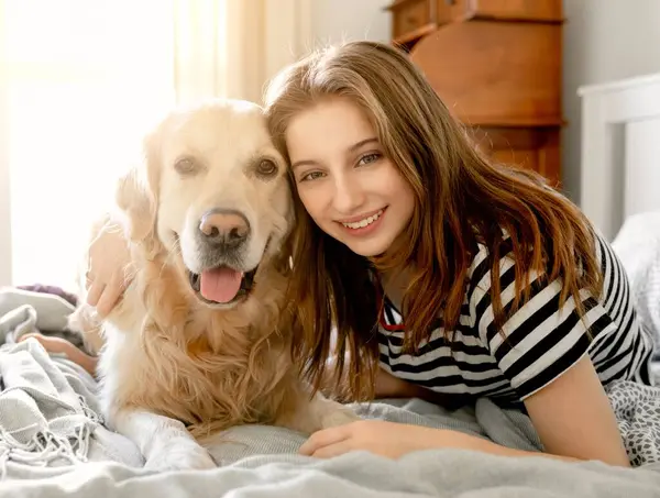 Ładna Dziewczyna Przytula Psa Golden Retrievera Uśmiecha Się Siedząc Łóżku — Zdjęcie stockowe