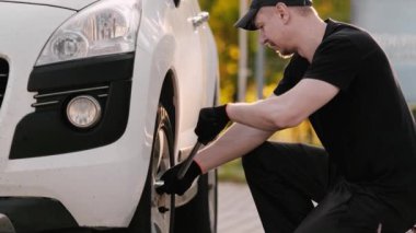 Tamirci, Wrench ile tekerlek cıvatasını sökmek için özenle çalışıyor.