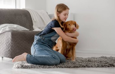 Küçük Kız Yerde Nova Scotia Retriever 'a sarıldı, Nova Scotia Retriever Toller