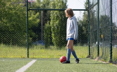 Kız futbol antrenmanı sırasında futbol sahasında topa liderlik ediyor.