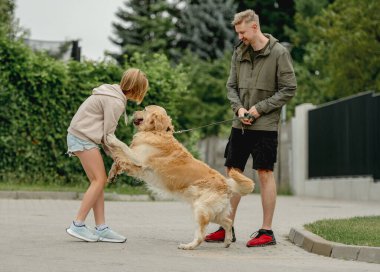 Baba ve kızı yürüyüş sırasında köpekleriyle oynuyorlar.