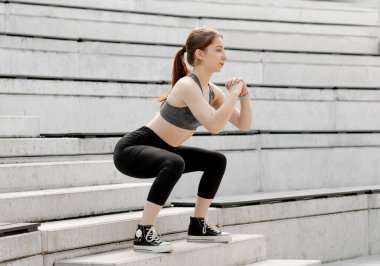 Kız temiz sabah havasında dışarıda çömeliyor.