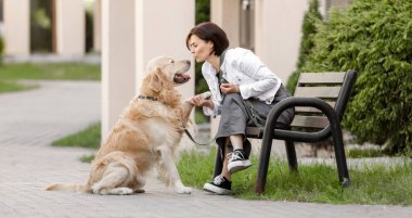 Kız, sıcak havalarda altın av köpeğiyle bankta dinleniyor.