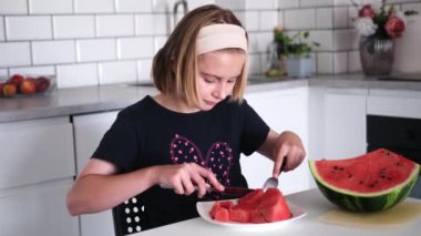 Kız mutfakta karpuz keser ve yer.