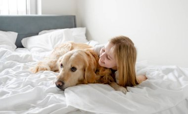 Küçük Kız Yatakta Beyaz Yatakta Altın Köpek ile Oynuyor