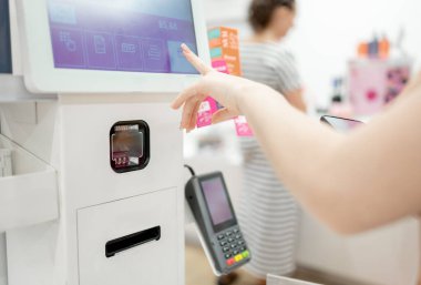 Kız self-servis kasasında satın almak için ödeme yapıyor, ellerin yakın çekimi.