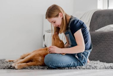 11 yaşındaki kız, Nova Scotia Retriever 'la evde oynuyor.