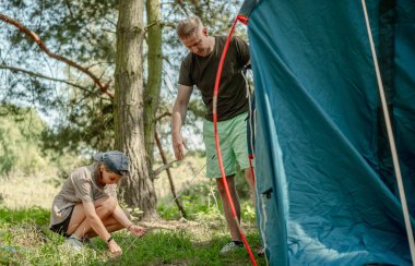 Baba ve kızı ormanda kamp yaparken bir çadır kuruyorlar.