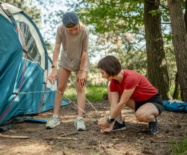Anne ve kızı yaz için ormanda çadır kuruyor.