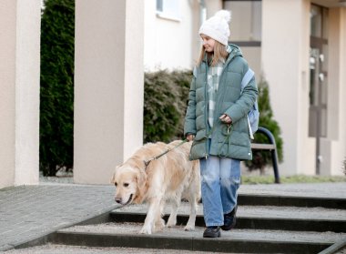 Baharın başında Yeşil Ceketli Kız Şehir Caddesinde Golden Retriever ile Yürüyüşü