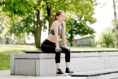 Sportif kız parkta koştuktan sonra nefesi kesiliyor.