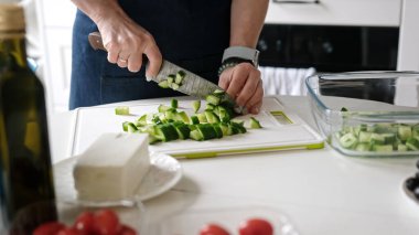 Mutfakta Bir Kadın Yunan Salatasını Hazırlayan Salatalıkları Kesiyor