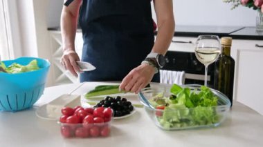 Kadın Elleri, Yunan salatası için bir bardak beyaz şarapla salatalık dilimliyor