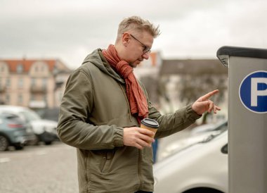 Man Uses Parking Meter In City Center clipart