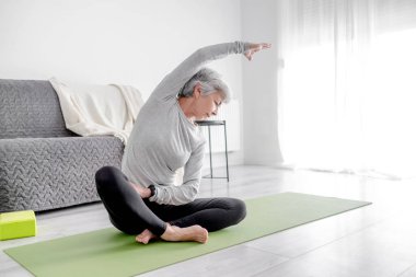 65 yaşındaki Sevimli Kadın Yoga minderinde Evde Egzersiz Yapıyor