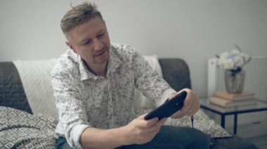 Genç adam evde akıllı telefon yarışında oyun oynuyor.