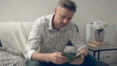 Genç adam pasaportunu evde gezdiriyor ve vizesini kontrol ediyor.