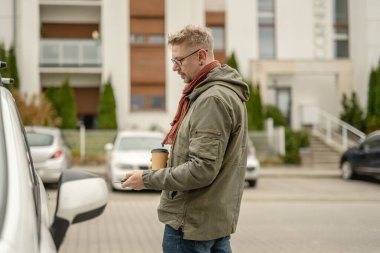 Genç Çekici Adam bir arabayı sokağa park eder ve kablosuz olarak açar.