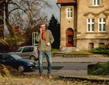 Sokakta gün batımında telefonda konuşan çekici genç adam.