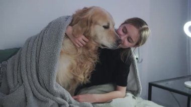 Tatlı küçük kız uyumadan önce altın av köpeğiyle yatakta oynuyor. Onlar mutlu, sevimli bir ikili.