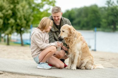 Babası olan kız yürürken Golden Retriever 'a içki veriyor.