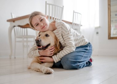 Gülümseyen, mutlu bir genç kız sarılıyor ve evinde sevimli bir köpek besliyor.