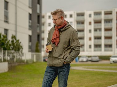 Genç Çekici Adam, Caddedeki bir apartmanın yakınındaki kahveden hoşlanıyor.