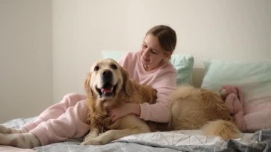 Sevimli küçük kız neşe içinde yatakta güzel bir köpekle oynuyor.