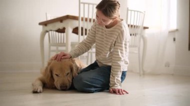 Genç kız mutluca sarılıyor ve evdeki mutfaktaki sevimli köpeğini okşuyor.