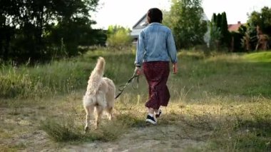 Bir kadının altın av köpeğiyle dışarıda dolaşması görüntüsü.
