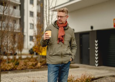 Genç ve çekici bir adam sabah kahvesini bir garajın yanında içiyor.